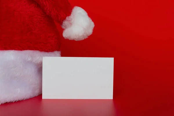 Sombrero de Santa Claus con una tarjeta en blanco buena para la prueba en rojo — Foto de Stock