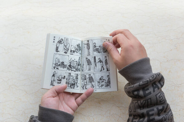 ZhongShan China-January 4:man reading a comic book named Old Master Q on January 4 2017.Old Master Q is a popular Hong Kong comic created by Alfonso Wong and appeared in 1962 and serialised in 1964.