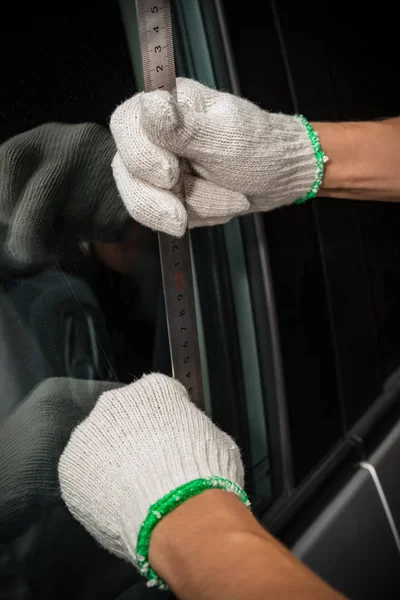 Mann mit Handschuh versucht Fahrzeugtüre mit Stahllineal zu öffnen — Stockfoto