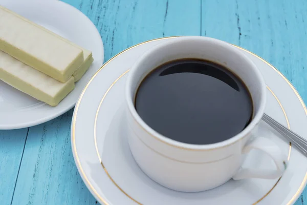Xícara de café e chocolate branco wafer em um chão azul — Fotografia de Stock