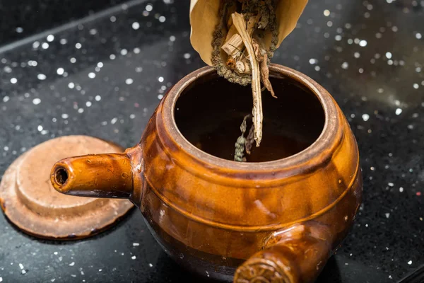 Poner hierbas en una olla de esmalte para decoctar la medicina herbal — Foto de Stock