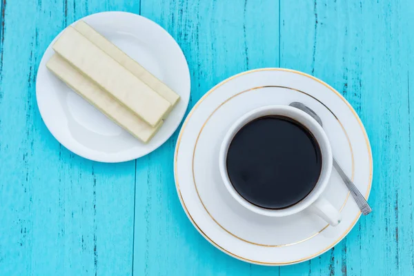 Vista dall'alto tazza di caffè e cialda di cioccolato bianco su un ackground blu — Foto Stock