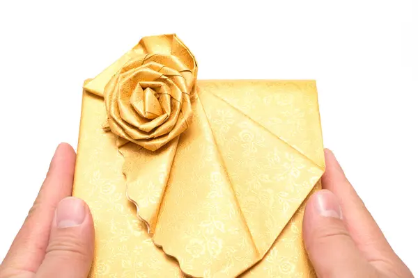 Mãos segurando uma caixa de presente dourado envolto no fundo branco — Fotografia de Stock