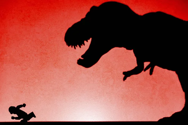 Shadow of tyrannosaurus chasing human  on wall no logo or trademark — Stock Photo, Image