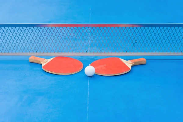 Pingpong rackets and ball and net on a blue pingpong table — Stock Photo, Image