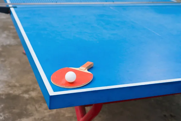 ピンポン ラケットとボール青いピンポン テーブルの上 — ストック写真