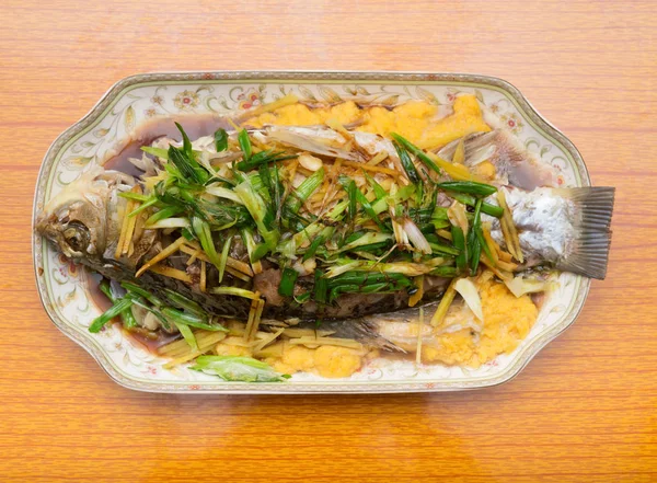 Φρέσκο ψάρι αχνιστό ολόκληρο καλυμμένο με βότανα κρεμμύδια και σάλτσα — Φωτογραφία Αρχείου