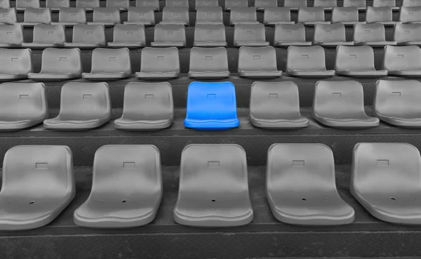 Stadium seats with one highlighted on blue — Stock Photo, Image