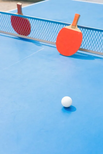 PingPong rakiety i piłki i net na niebieski pingpong tabeli — Zdjęcie stockowe