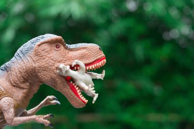 devasa tyrannosaurus ağaçların önünde küçük bir dinozor yakalar