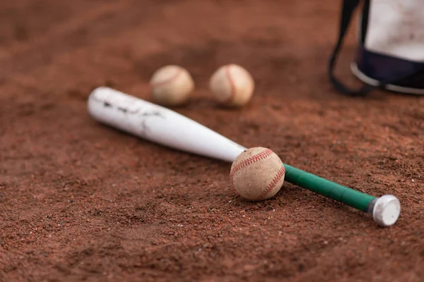 Basebollträ och bollar och en väska på golvet — Stockfoto