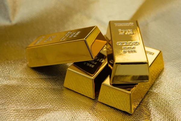 Four pieces of gold bars on a golden background — Stock Photo, Image