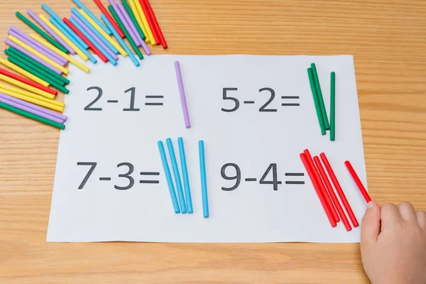 Kid learning simple subtraction by counting numbers of sticks — Stock Photo, Image