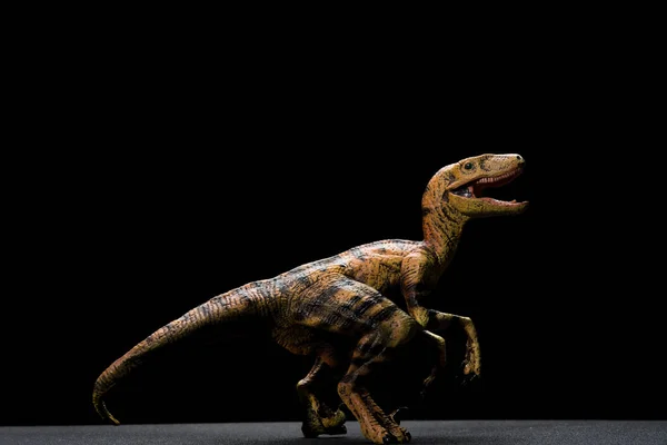 Yan görünümü sarı velociraptor oyuncak karanlık bir arka plan üzerinde — Stok fotoğraf