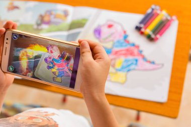 Augmented Reality popup resim yolu ile hareket eden dolu bir dinozor oynayan çocuk