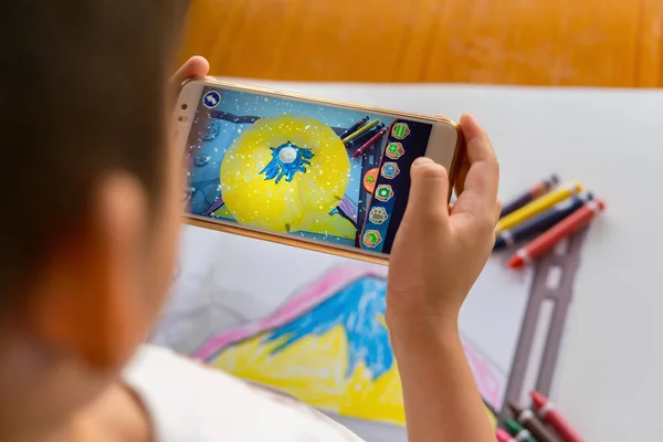 Ребенок играет дополненную реальность всплывающие картины заполненной горы с помощью мобильного телефона — стоковое фото