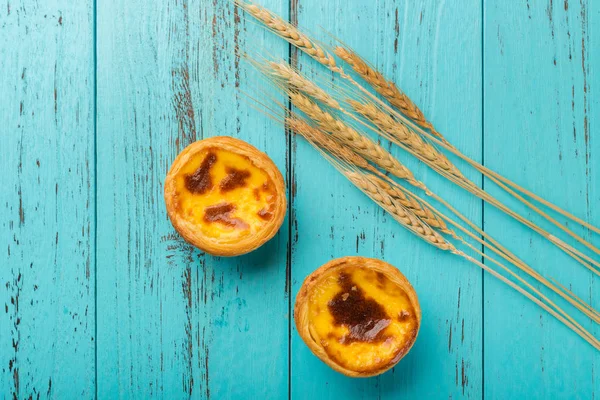 Bovenaanzicht studio shoot van Portugese ei taarten op hout met tarwe op achtergrond — Stockfoto