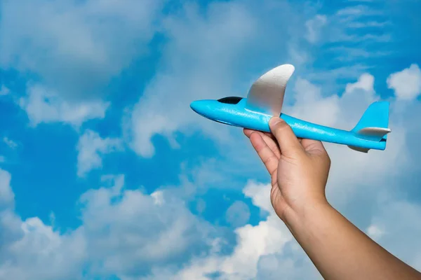 Hand lyfta upp en blå flygplan modell under himmel — Stockfoto