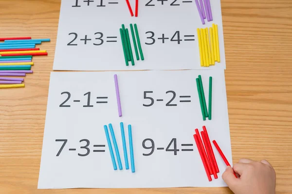 Kind lernt einfache Subtraktion und Addition durch Zählen von Stäbchen — Stockfoto