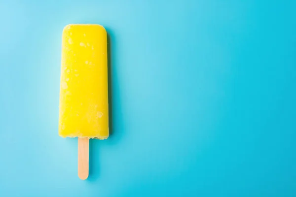 Gele popsicle op een blauwe achtergrond — Stockfoto