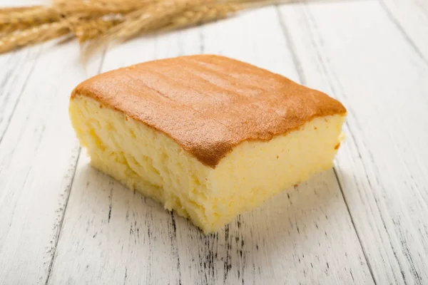 白色木背景上小麦的海绵蛋糕 — 图库照片