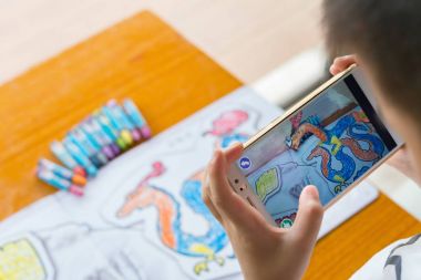 Augmented Reality popup resim yolu ile hareket eden bir renk dolu ejderha oynayan çocuk