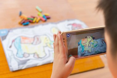Augmented Reality popup resim yolu ile hareket eden bir renk dolu filin oynayan çocuk