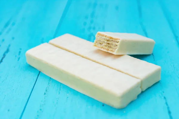 Side view white chocolate wafer with cut out sections on a blue background — Stock Photo, Image