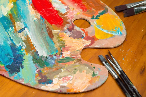 Paintbrush and filled palette on wood table — Stock Photo, Image