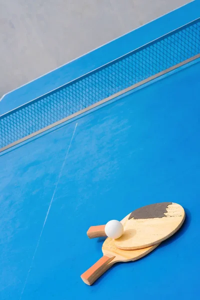 Viejas raquetas de pingpong y pelota y red sobre una mesa de pingpong azul —  Fotos de Stock