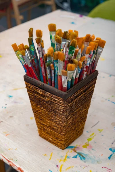 Paintbrushes and basket on a wood table — Stock Photo, Image