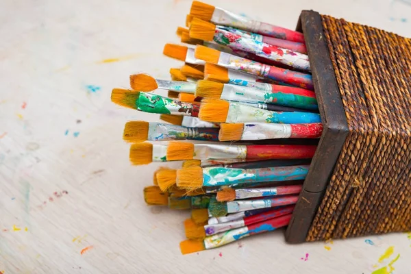 Paintbrushes and basket on a wood table — Stock Photo, Image