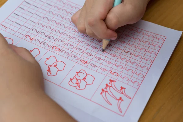 Το παιδί μαθαίνει να γράψει αραβικά ψηφία από τους παρακάτω οδηγούς — Φωτογραφία Αρχείου