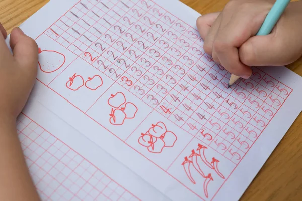 Kid learns to write Arabic numerals by following guides — Stock Photo, Image