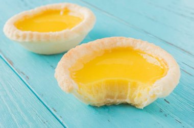 bir ısırık ve ahşap bir arka plan üzerinde tam bir ile iki yumurta tart bir stüdyo çekimleri