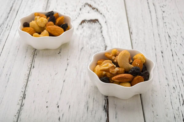 two dishes of almonds and walnuts and cashew nuts and raisin and dry blueberries