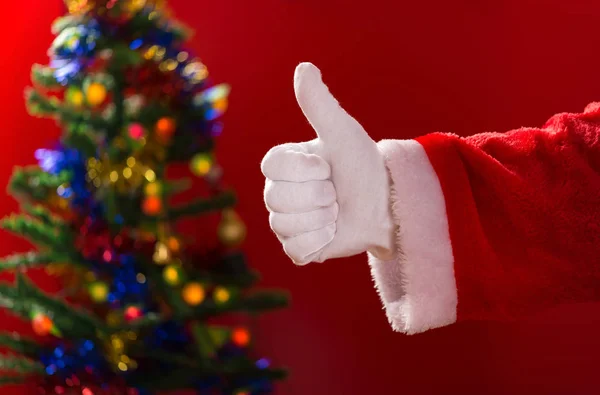 親指の背景に飾られたクリスマス ツリーでジェスチャーをしているサンタ クロース — ストック写真