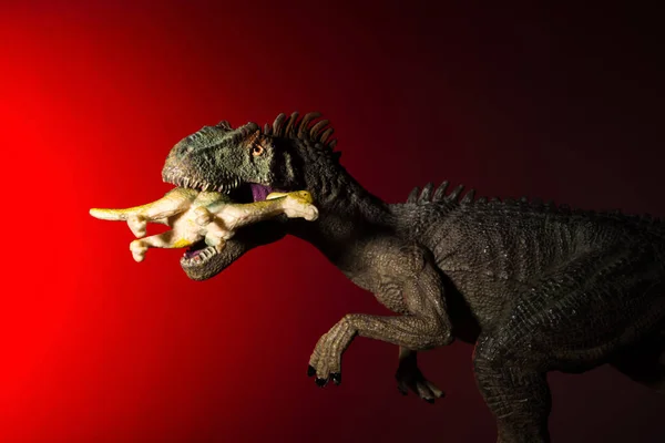 异咬一只小恐龙 头上有聚光灯 背景上是红灯 — 图库照片