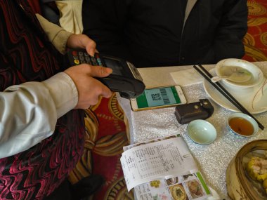 Zhongshan,China-February 1, 2018:doing payment at a restaurant via Wechat money on mobile.Wechat or Alipay for payment and money transfering via mobile becomes very common and popular in China,fast and safe. clipart