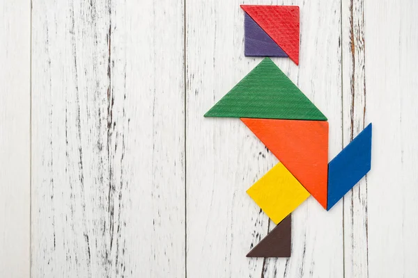 wooden tangram shaped like a people skating on white with copy space