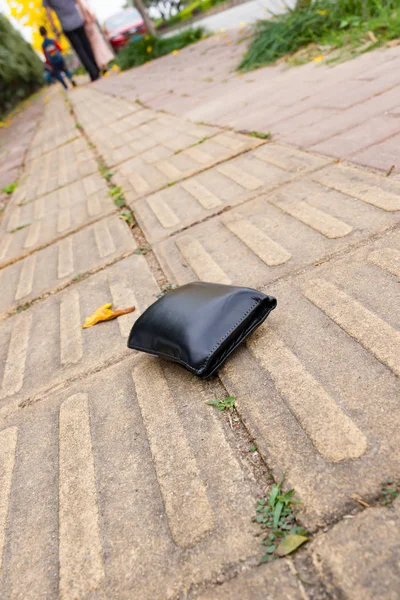lost wallet on sidewalk with people going far away
