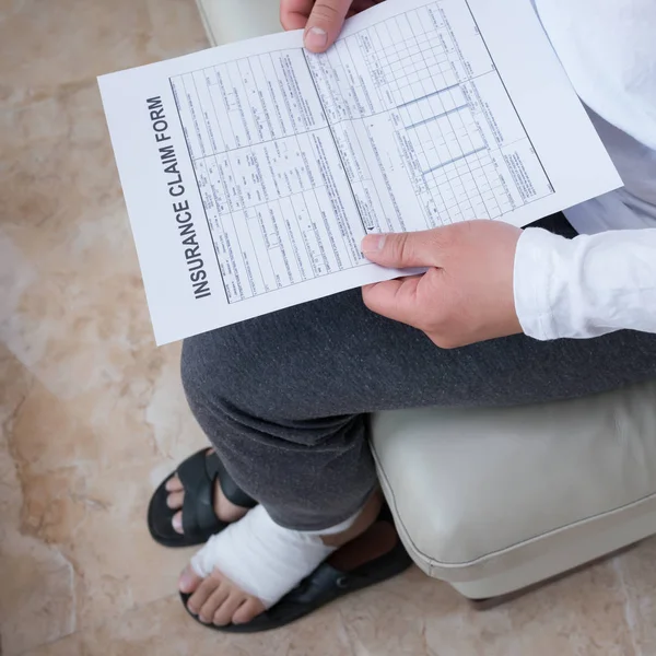 Man Wrapped Foot Sitting Sofa Reading Work Insurance Claim Form — Stock Photo, Image