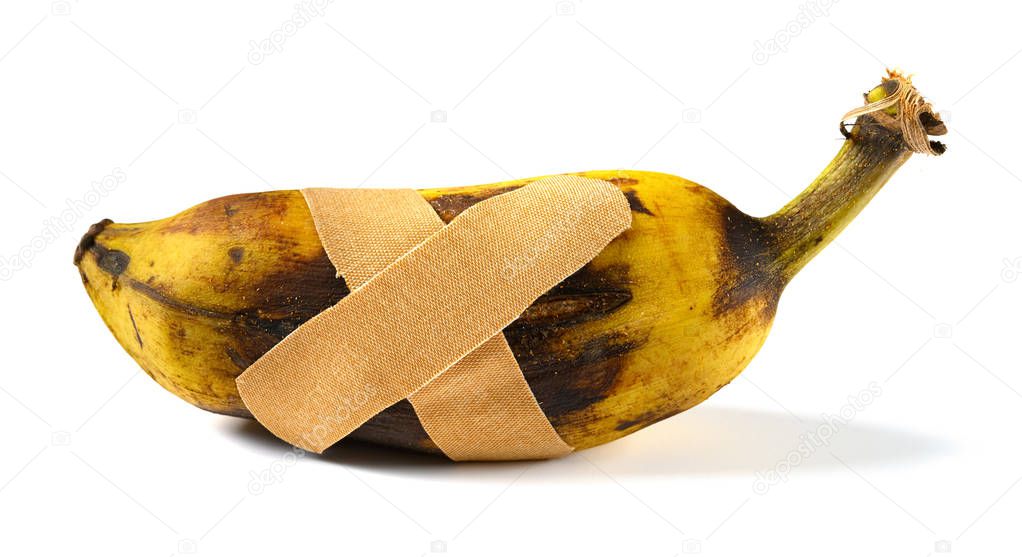 overripe and cracked banana with plaster on white background