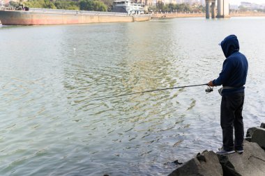 Nehrin kenarında duran ve balık tutan bir adam