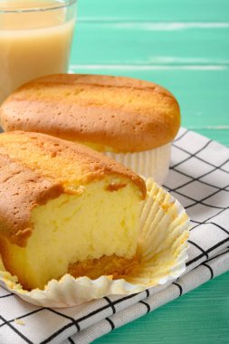 İki fincan kek ve bir tanesinde ısırık ve bir fincan soya sütü var.