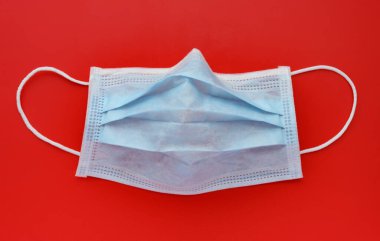Kırmızı arka planda kullanılmış tıbbi yüz maskesi dışında