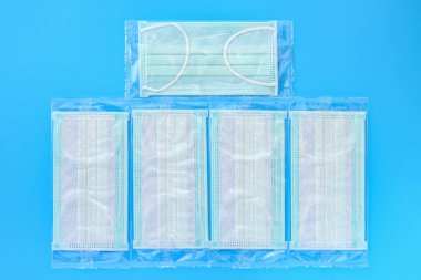 Tek kullanımlık yepyeni tıbbi yüz maskeleri mavi arka planda