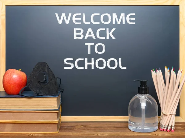 black board with back to school and safety mask for children and instant hand sanitizer nearby, removeable words contain paths, concept of avoiding attack of infectious disease in the school