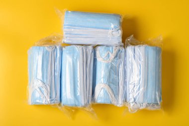 Sarı arka planda 5 paket tıbbi yüz maskesi.
