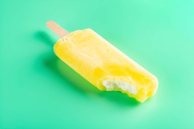 Açık yeşil zemin üzerinde büyük bir ısırık olan sarı buzlu şeker.